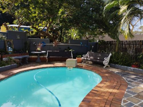a swimming pool in a yard with a bench next to it at Tuksumduin in Ballito