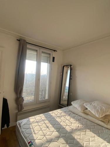 une chambre avec un lit et une grande fenêtre dans l'établissement Appartement ensoleillé, central et tout équipé avec vue Tour Eiffel et Panthéon, à Paris