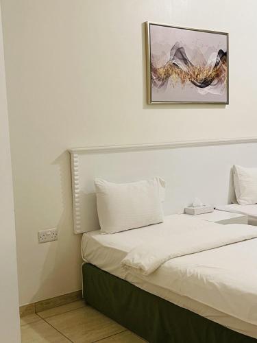 two beds in a room with a picture on the wall at Husin Al Khaleej Hotel Apartment in Seeb