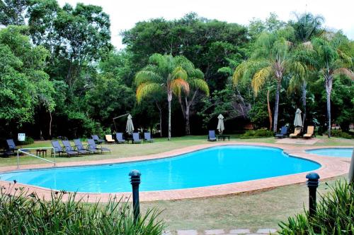 a swimming pool in a park with palm trees at Kruger Park Lodge - AM8 - 3 Bedroom Chalet in Hazyview
