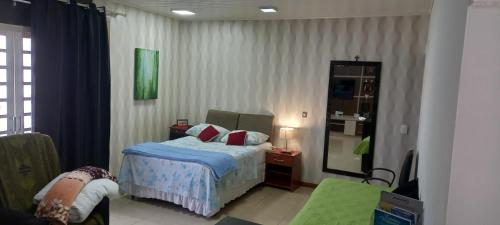 1 dormitorio con cama y espejo en Estúdio central PG1 prox Paladium, en Ponta Grossa