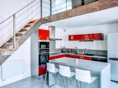 une cuisine avec des placards rouges et un escalier dans l'établissement Loft Naturalia, à Avignon