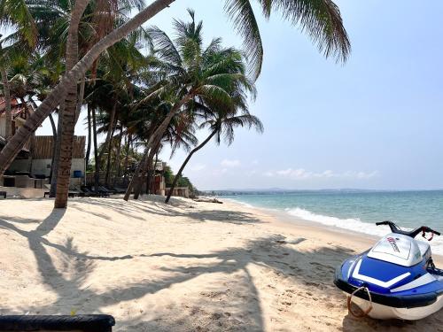 a blue motorcycle parked on a beach with palm trees at Sunsea Resort in Mui Ne