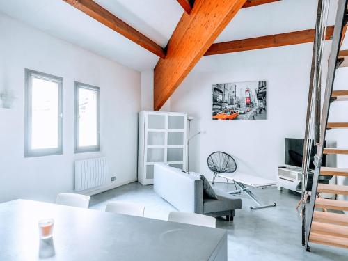 Elle comprend un salon doté de murs blancs et d'un plafond en bois. dans l'établissement Loft Naturalia, à Avignon