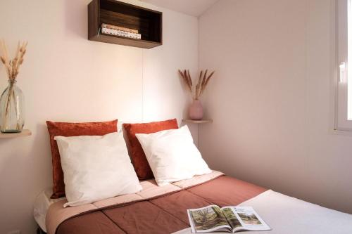 a bedroom with a bed with white and orange pillows at L'Orée de l'Océan - Vendée in Landevieille