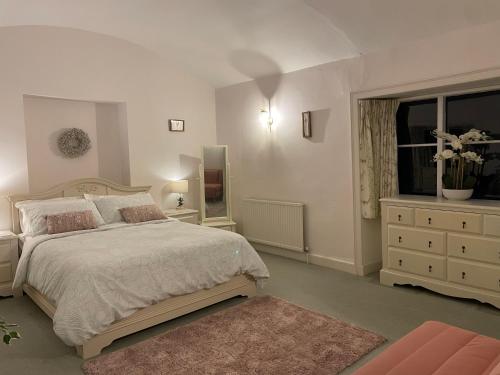 - une chambre avec un lit, une commode et une fenêtre dans l'établissement Cupcake Cottage: Quintessential Cotswold Cottage, à Nailsworth