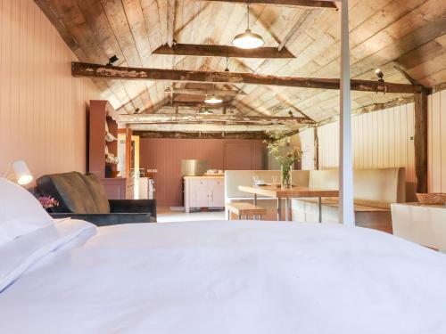 een slaapkamer met een wit bed en een woonkamer bij The Stone Barn in Ticehurst