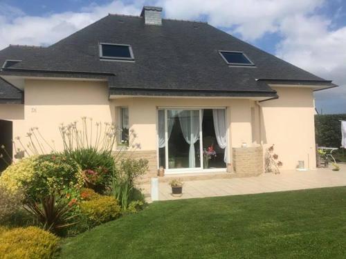 une maison blanche avec une grande fenêtre dans une cour dans l'établissement Dom & ses chambres d'hôtes, à Plouigneau