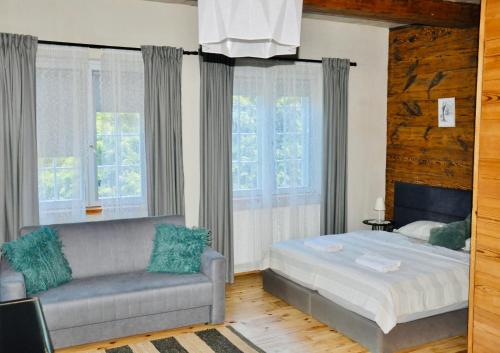 a bedroom with a bed and a couch and windows at Dom Podcieniowy na Żuławach Wiślanych in Nowy Dwór Gdański