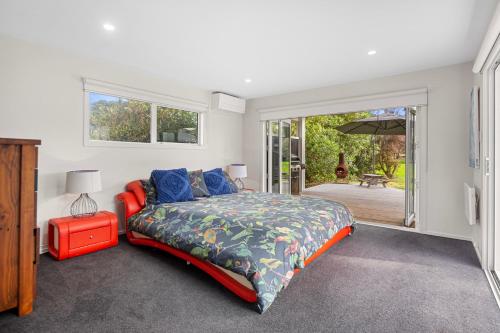 Changing Sands - Whiritoa Holiday Home في Whiritoa: غرفة نوم بسرير وباب للباحة