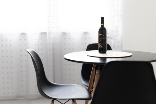 a table with a bottle of wine and two chairs at Apartment Ivka in Osijek