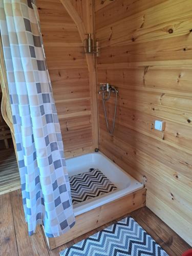 een bad in een houten kamer met een douche bij Lini Guest House in Nīca