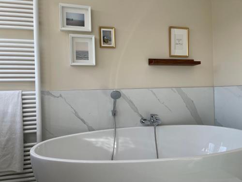 a white bath tub in a bathroom with pictures on the wall at Villa Lighthouse in Callantsoog