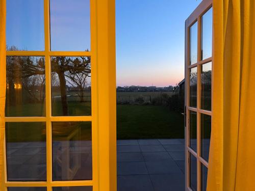 an open window with a view of a yard at Villa Lighthouse in Callantsoog