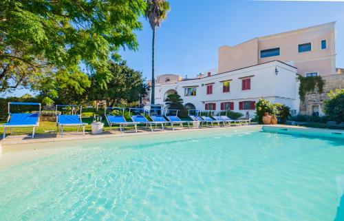 una piscina con sedie blu e un edificio di Villa Luritu Luxury Pool Tricase by HDSalento a Tricase