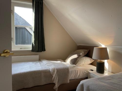 een slaapkamer met 2 bedden en een raam bij Villa Lighthouse in Callantsoog
