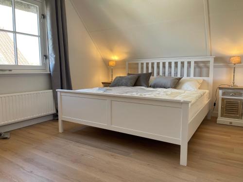 a large white bed in a room with a window at Villa Lighthouse in Callantsoog