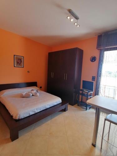 TaurisanoにあるGagliardo Houseのオレンジ色の壁のベッドルーム1室、ベッド1台、テーブルが備わります。