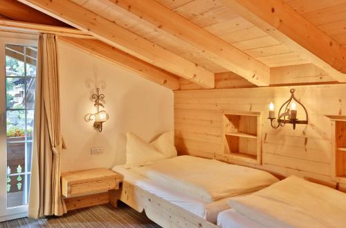 a bedroom with two beds in a wooden room at ERMITAGE Wellness- & Spa-Hotel in Gstaad