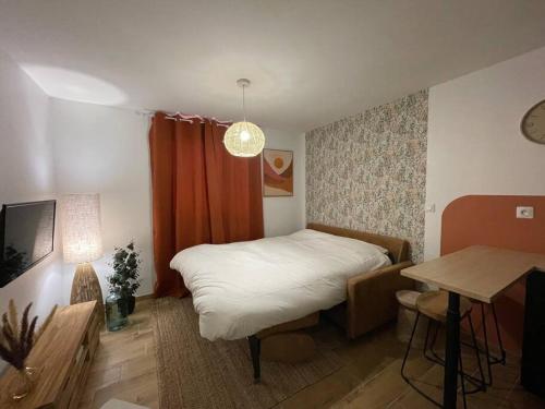 Dormitorio pequeño con cama y mesa en Magnifique Studio Calais Plage, en Calais