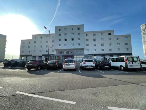 un estacionamiento con autos estacionados frente a un edificio en Magnifique Studio Calais Plage, en Calais