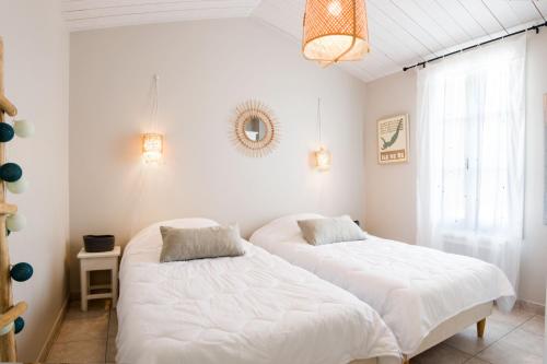 deux lits dans une chambre aux murs blancs dans l'établissement AGAPANTHES Jolie Maison proche Plage et Commerces, au Bois-Plage-en-Ré