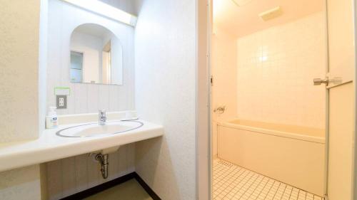 a bathroom with a sink and a bath tub at Hotel Yunotaniso in Uonuma