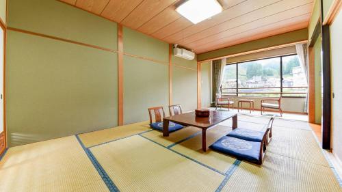 a room with a table and chairs and a window at Hotel Yunotaniso in Uonuma