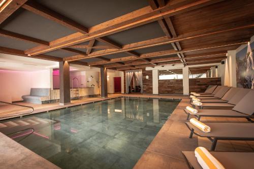 a swimming pool with lounge chairs in a building at Hotel Gissbach in Brunico