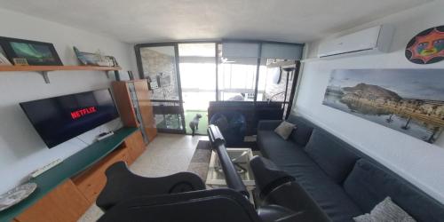 Il comprend un salon doté d'un canapé et d'une télévision à écran plat. dans l'établissement Apartamentos Santabarbara, à Alicante
