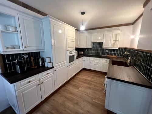 eine Küche mit weißen Schränken und schwarzen Arbeitsplatten in der Unterkunft Bel appartement Samoëns 72m2 in Samoëns