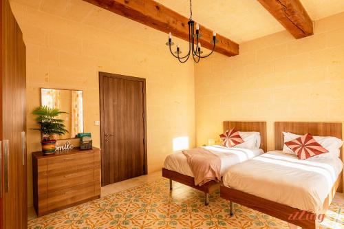1 dormitorio con 2 camas y lámpara de araña en A charming Gozo Farmhouse in Sannat, en Sannat