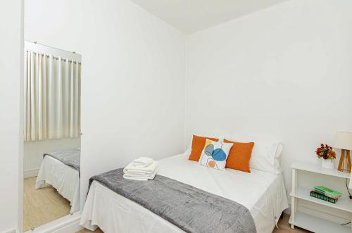 庫里奇巴的住宿－Três Quartos, Gigante e confortável Próximo ao Hard Rock Café no Batel，卧室拥有白色的墙壁,配有带橙色枕头的床。