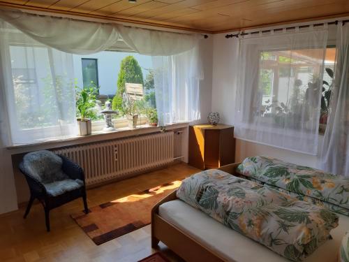 uma sala de estar com um sofá, uma cadeira e janelas em Schöne 80qm Ferienwohnung in ruhiger Lage em Friedrichshafen