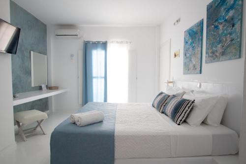 a white bedroom with a bed and a window at Alloro Perissa in Perissa