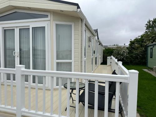 a house with a deck with a chair on it at Ingoldmells Sunnymede I14 in Ingoldmells