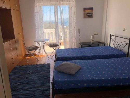 two beds with blue sheets in a room with a window at Nikolas house in Megalochori