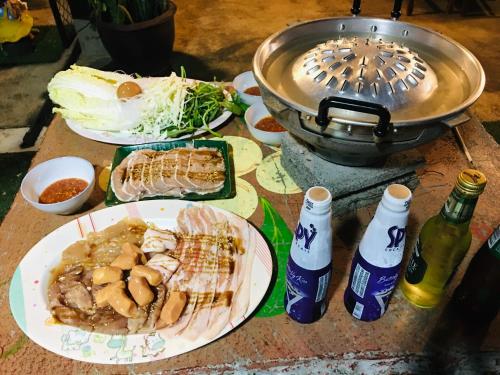 a table with plates of food and a pot of food at Baan Dongsak River view in Sangkhla Buri