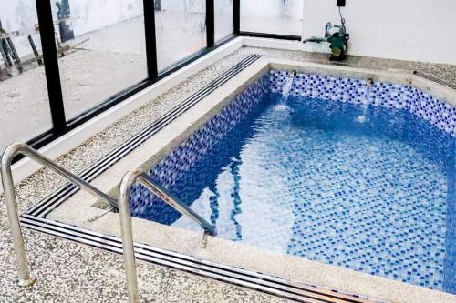 een zwembad met blauwe tegels voor een raam bij Tanjung Jara Cottage - with indoor pool in Dungun