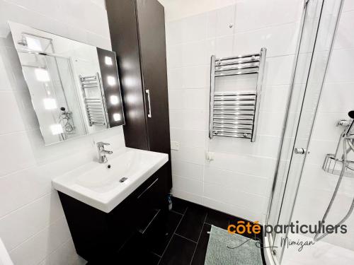 a bathroom with a sink and a mirror and a shower at AU PETIT LOGIS - Apt T1 Bis avec terrasse à 500m de l'Océan in Mimizan