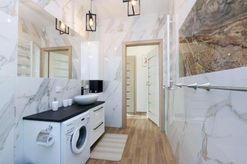 a bathroom with a washing machine and a sink at Bursztynowe Tarasy - Apartamenty in Gdańsk