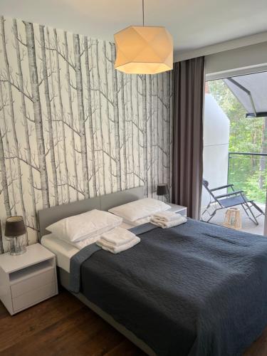 una camera da letto con un letto e carta da parati ad albero di Sosnowe Apartamenty - Marina 2 a Augustów