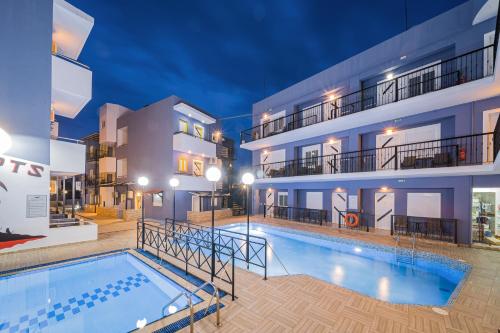a swimming pool in front of a building at night at Happy Days in Malia
