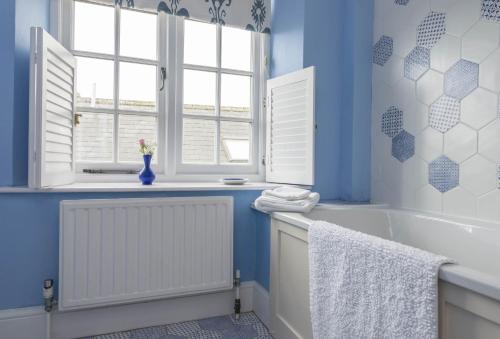 Hearn Lodge في نيثر ستوي: حمام به جدران زرقاء وحوض استحمام ونافذة
