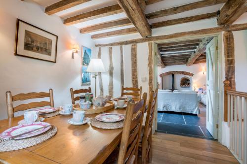 a dining room with a wooden table and a bedroom at Lletty in Eglwys-Fâch