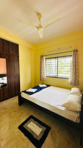 ein großes Bett in einem Zimmer mit Fenster in der Unterkunft Navile Apartments in Chikmagalur