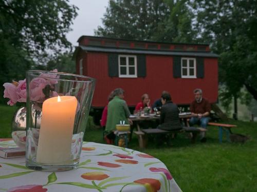 uma vela sobre uma mesa com uma casa ao fundo em Bauwagen unterm Birnbaum em Lennestadt