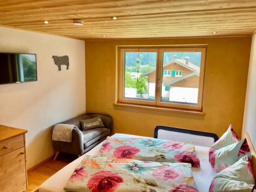 a bedroom with a bed and a chair and a window at Alpenzauber Apartment Montafon in Sankt Gallenkirch