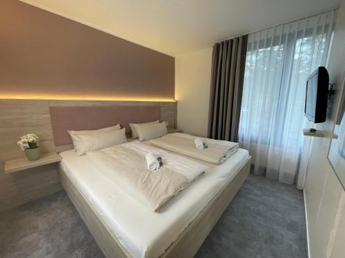 a bedroom with a large white bed with a television at Hotel Park Soltau in Soltau