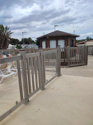 une clôture en bois sur une terrasse avec une maison dans l'établissement Mobil home, à Port-la-Nouvelle